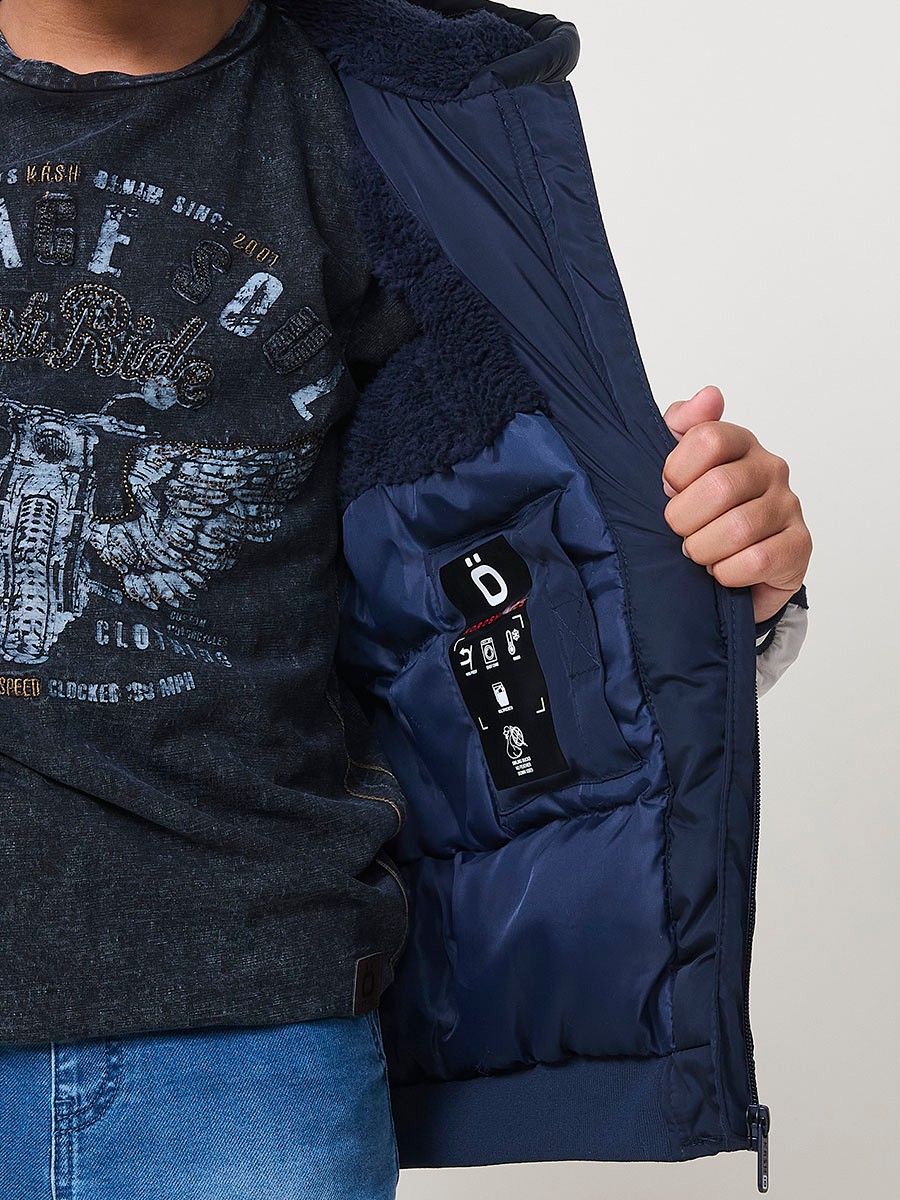 Blouson matelassé pour garçon, coloris navy avec capuche. Chaud et confortable, idéal pour l’hiver.