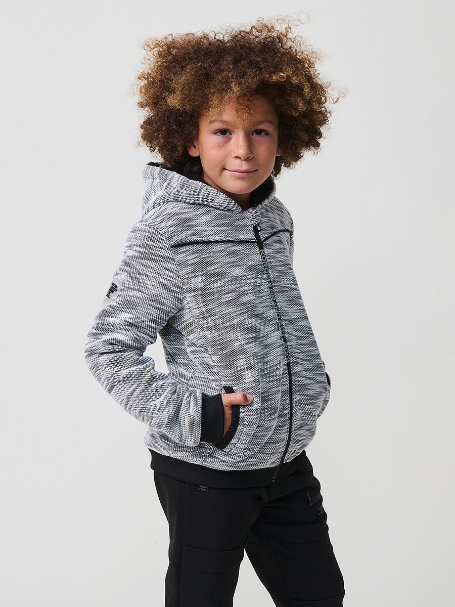Veste en maille spéciale pour garçon, coloris noir et écru, avec capuche doublée effet fourrure et intérieur matelassé.