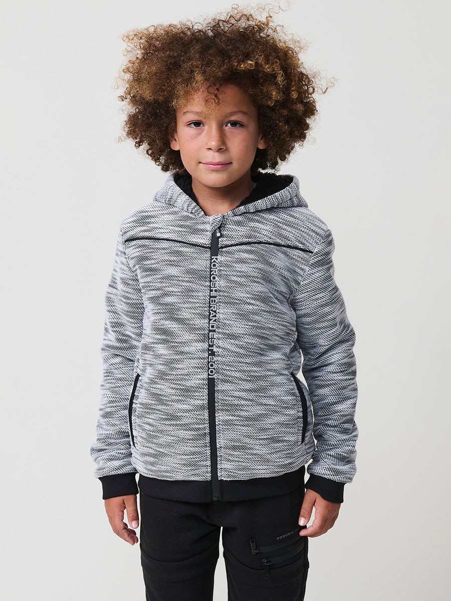Veste en maille spéciale pour garçon, coloris noir et écru, avec capuche doublée effet fourrure et intérieur matelassé.
