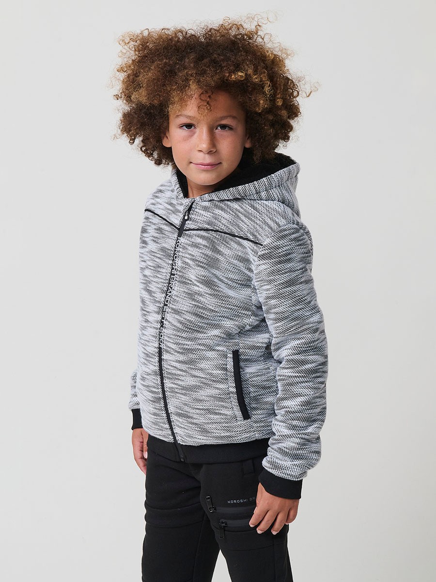 Veste en maille spéciale pour garçon, coloris noir et écru, avec capuche doublée effet fourrure et intérieur matelassé.