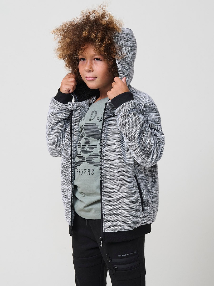 Veste en maille spéciale pour garçon, coloris noir et écru, avec capuche doublée effet fourrure et intérieur matelassé.