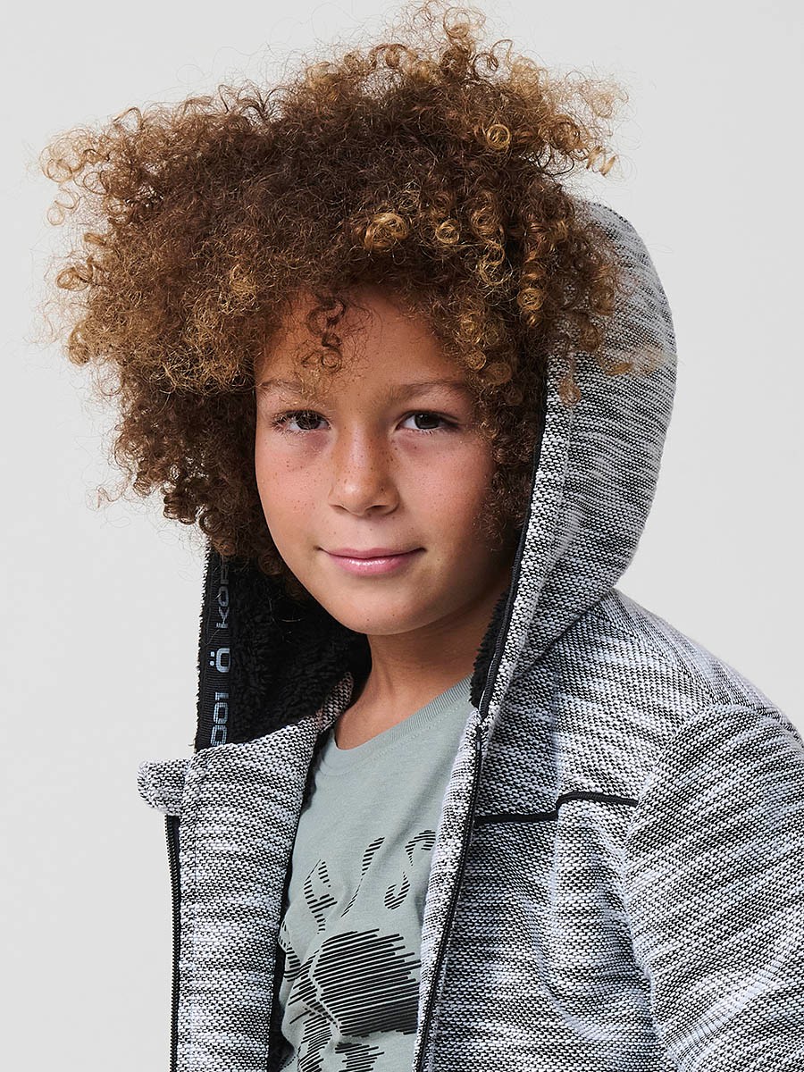 Veste en maille spéciale pour garçon, coloris noir et écru, avec capuche doublée effet fourrure et intérieur matelassé.