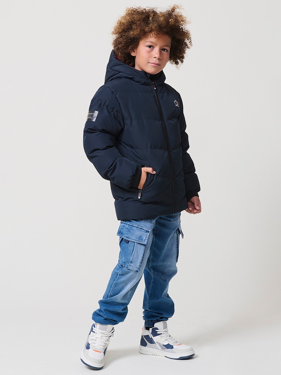 Blouson matelassé garçon en coloris navy avec capuche effet fourrure et fermeture zippée. Chaud et confortable.