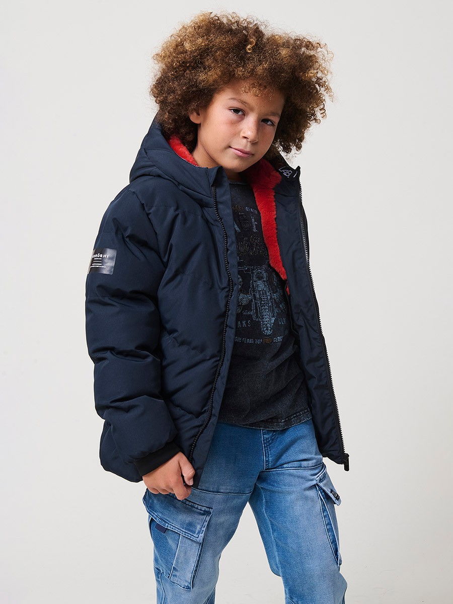 Blouson matelassé garçon en coloris navy avec capuche effet fourrure et fermeture zippée. Chaud et confortable.