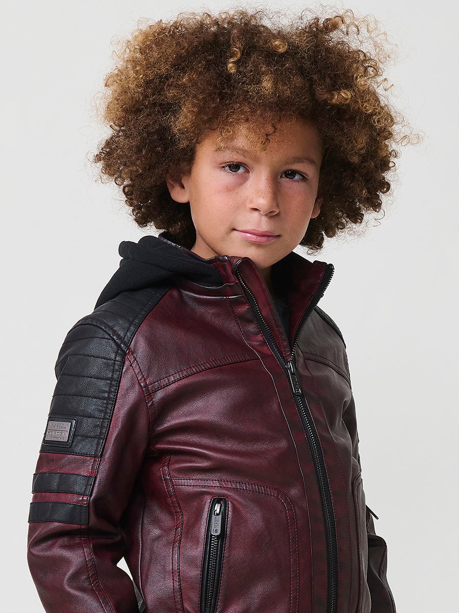 Cazadora de niño estilo motorista en color vino y negro efecto envejecido. Confeccionada en 100% poliéster con cierre de cremallera.