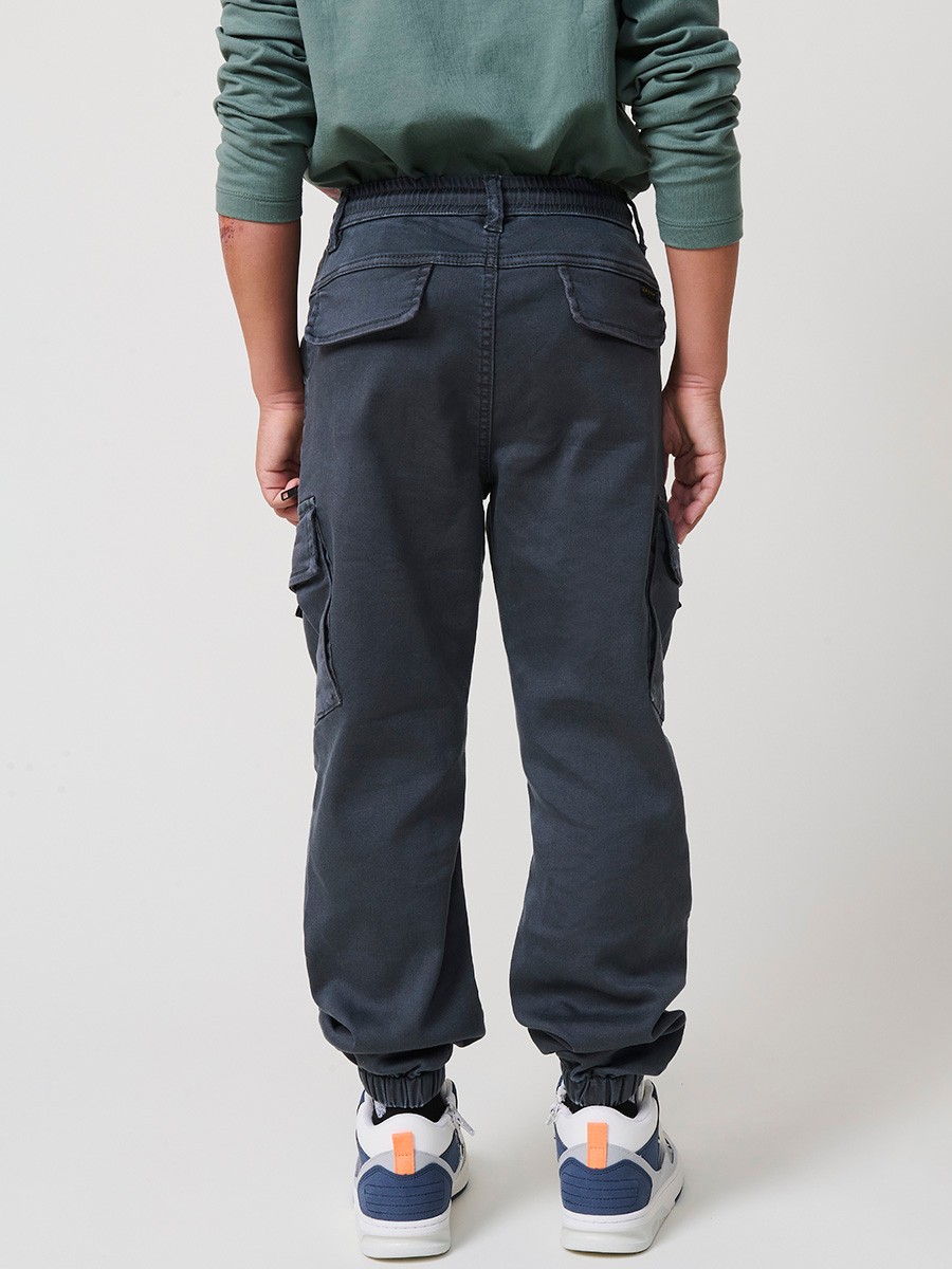 Pantalón jogger de niño en knit denim elástico color verde con bolsillos cargo. 100% algodón, cómodo y moderno.