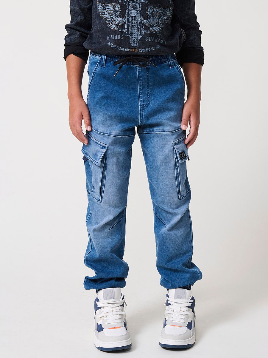 Pantalón jogger de niño en knit denim elástico color azul medio efecto lavado con bolsillos cargo. 100% algodón, cómodo y moderno.
