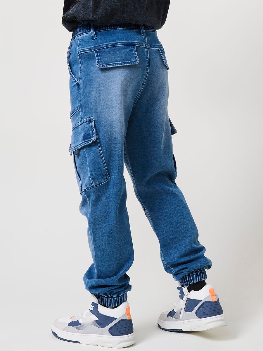 Pantalón jogger de niño en knit denim elástico color azul medio efecto lavado con bolsillos cargo. 100% algodón, cómodo y moderno.