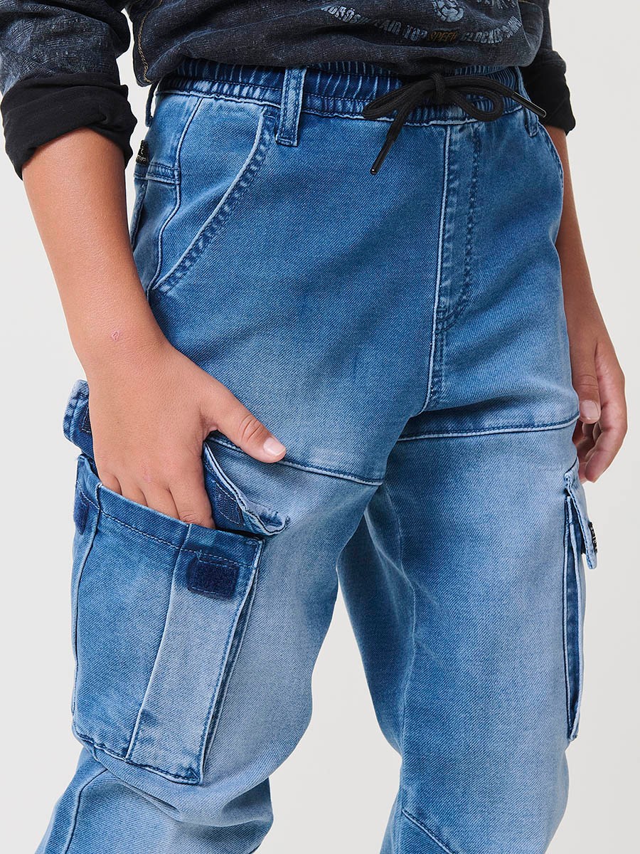 Pantalón jogger de niño en knit denim elástico color azul medio efecto lavado con bolsillos cargo. 100% algodón, cómodo y moderno.