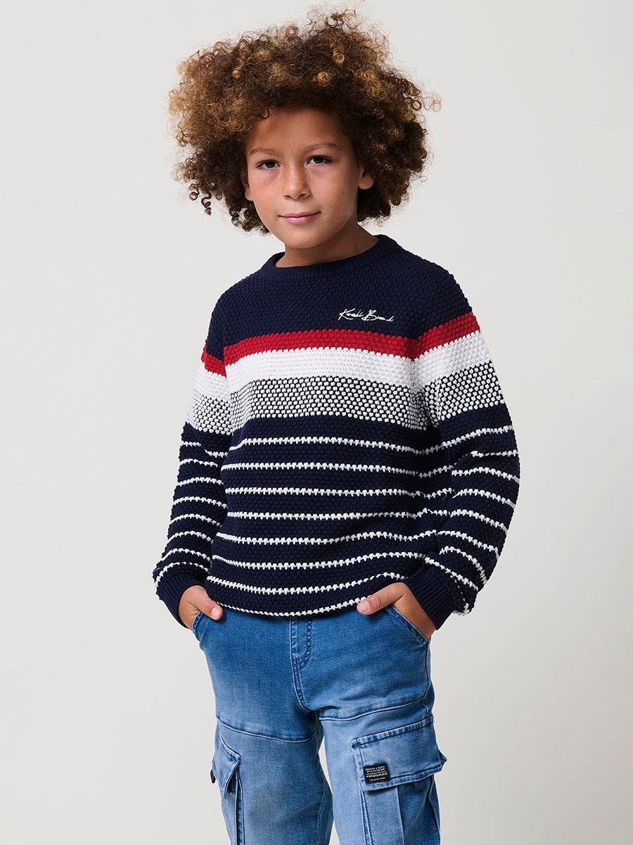 Jersey de niño en punto de algodón color navy con rayas crudo y rojas, cuello redondo y puños acanalados.