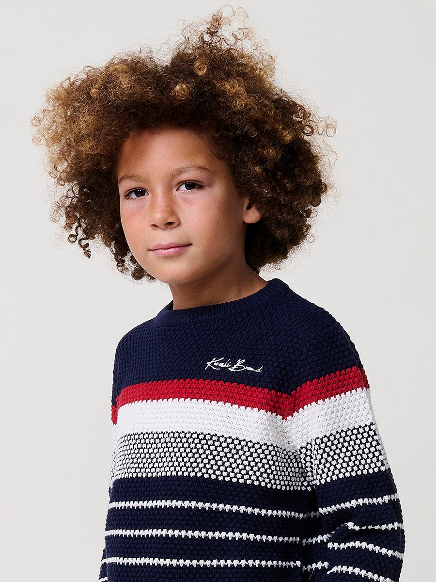 Jersey de niño en punto de algodón color navy con rayas crudo y rojas, cuello redondo y puños acanalados.