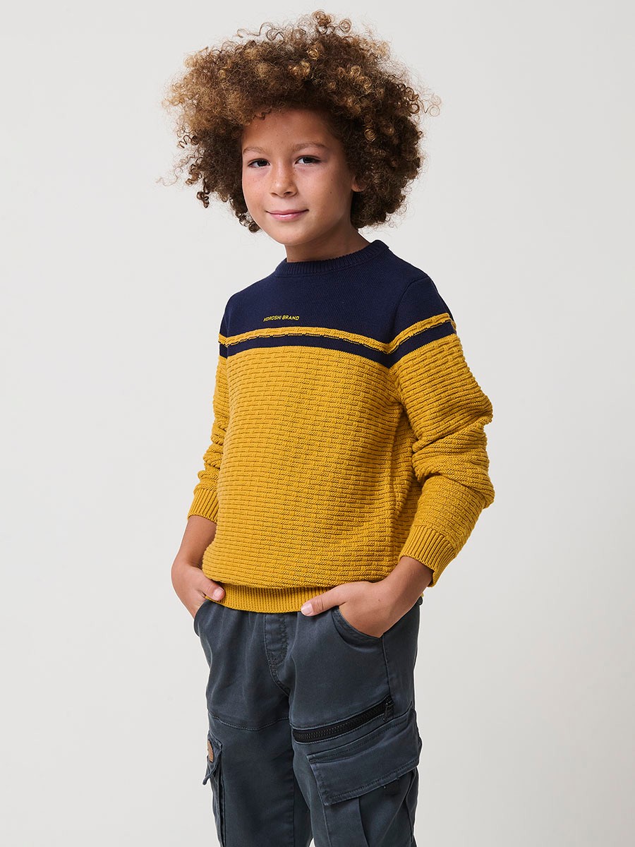 Jersey de niño en punto fantasía de algodón color mostaza con franja superior, cuello redondo y puños de canalé.