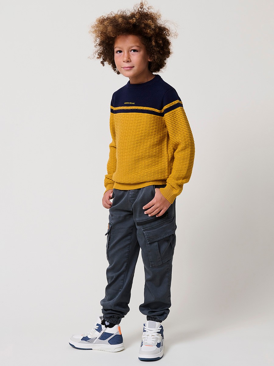 Jersey de niño en punto fantasía de algodón color mostaza con franja superior, cuello redondo y puños de canalé.