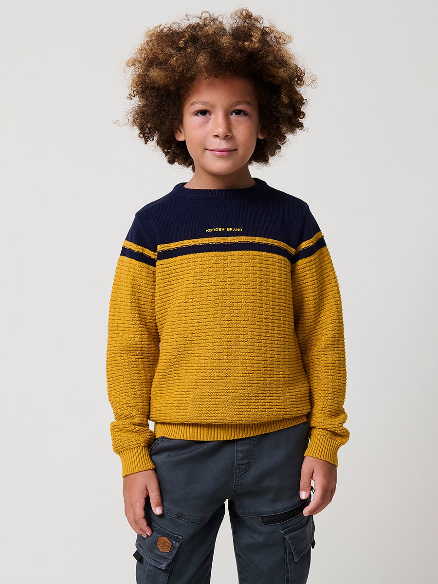 Jersey de niño en punto fantasía de algodón color mostaza con franja superior, cuello redondo y puños de canalé.