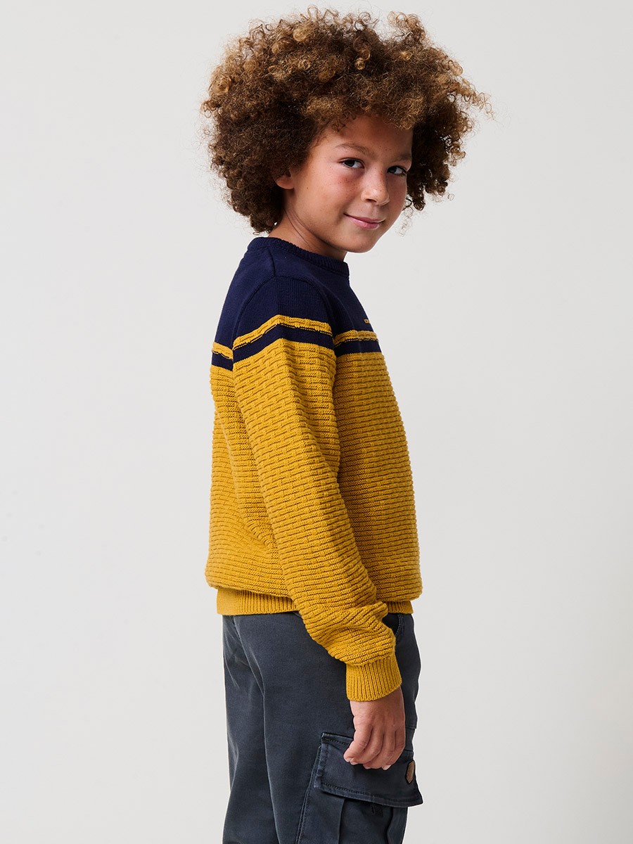 Jersey de niño en punto fantasía de algodón color mostaza con franja superior, cuello redondo y puños de canalé.