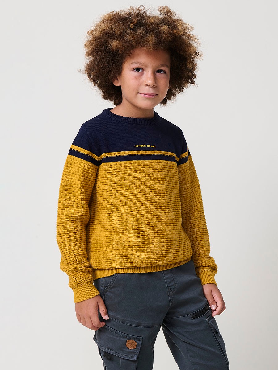Jersey de niño en punto fantasía de algodón color mostaza con franja superior, cuello redondo y puños de canalé.