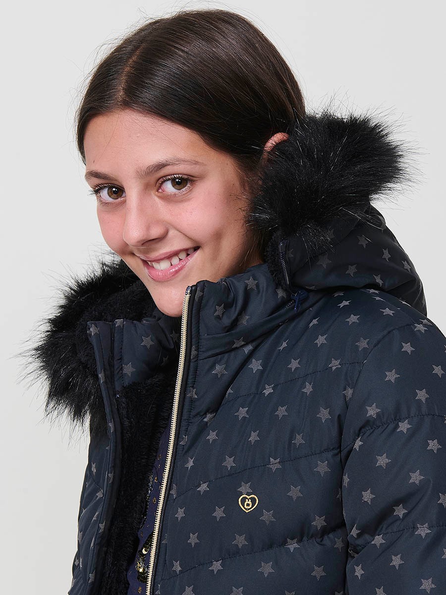 Chaqueta acolchada de niña en color navy con estampado de estrellas flocadas, cuello alto, capucha desmontable con pelo sintético y puños de canalé.